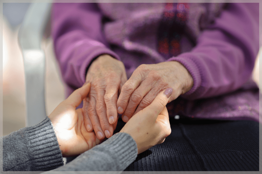 Eldercare At Home - Younger person holding older woman's hands in hers - MeetCaregivers