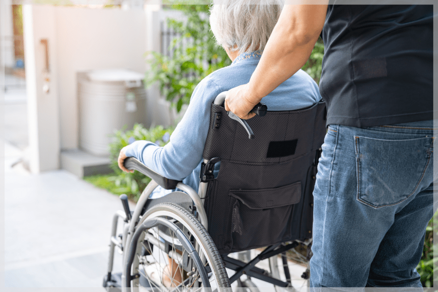 Consumer direction - Caregiver pushing elderly woman in a wheelchair outside - MeetCaregivers