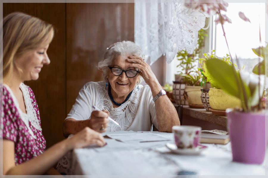Consumer direction - Elderly woman and her adult daughter filling out paperwork at the kitchen table - MeetCaregivers