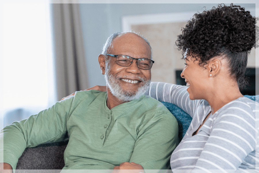 Care at home - Adult daughter and elderly father laughing together on the couch - MeetCaregivers
