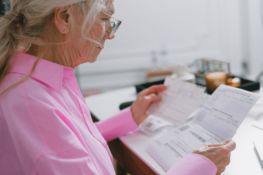 Elderly woman reviewing paperwork while spring cleaning.