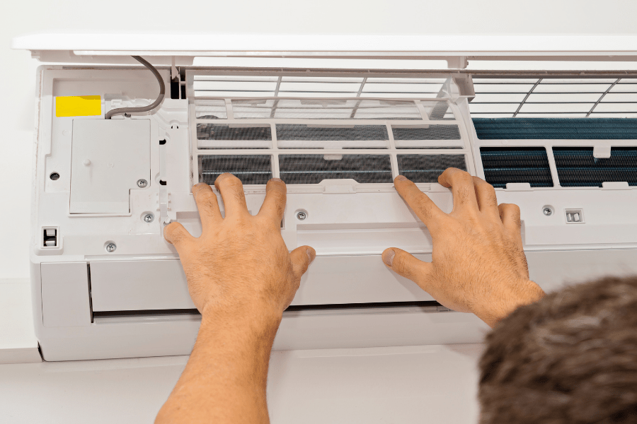 Man replacing the air filter on an air conditioner for spring cleaning.